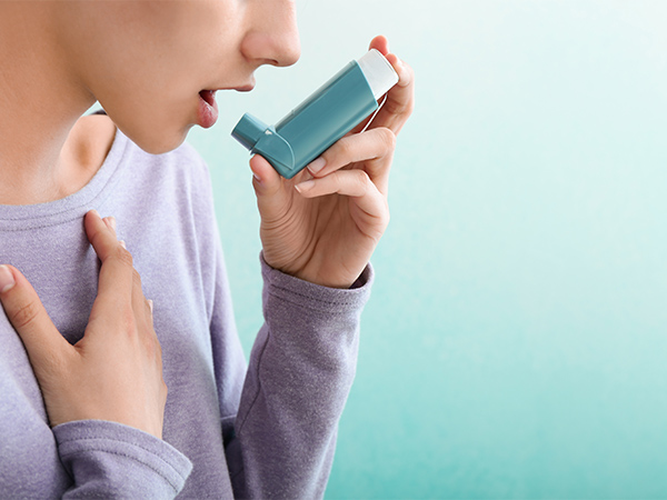 喘息に対して吸入器を使用する若い女性